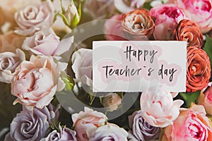 Gift card with the inscription happy teacher`s day in a bouquet of bright beautiful multi-colored roses