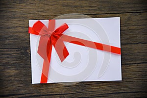 Gift card on wooden background / Pink white Gift card decorated with red ribbon bow