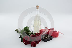 Gift, chocolate box, roses and champagne bottle on white background