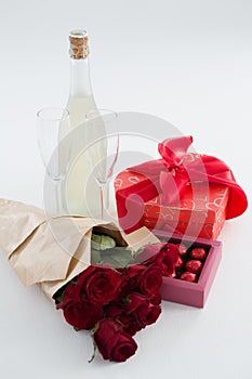 Gift, chocolate box, roses and champagne bottle on white background