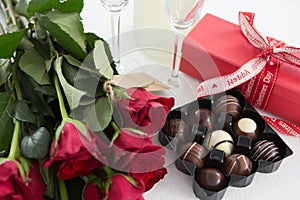 Gift, chocolate box, roses and champagne bottle on white background