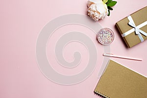 A gift concept with brown box, brown book, pen and flower over the pink background.
