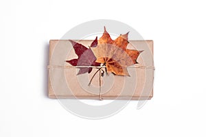 Gift in craft paper with autumn leaves on a white background, package, delivery, autumn mood, surprise