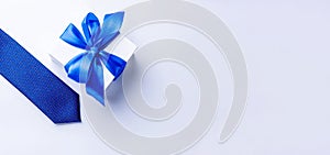Gift dad. Blue bowtie or tie, white box with bow ribbon on light background. Happy loving family and Fathers Day concept