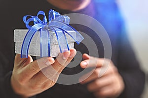 gift giving,man hand holding a gift box in a gesture of giving.blured background