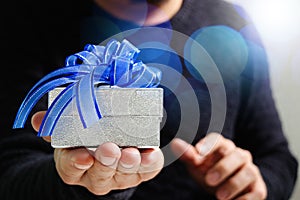 gift giving,man hand holding a gift box in a gesture of giving.blured background,bokeh effect