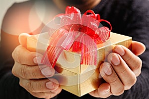gift giving,man hand holding a gift box in a gesture of giving.blured background