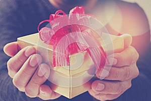 gift giving,man hand holding a gift box in a gesture of giving.blured background