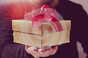 gift giving,man hand holding a gift box in a gesture of giving.blured background,bokeh effect