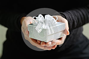 gift giving,man hand holding a gift box in a gesture of giving.blurred background,bokeh effect,vintage