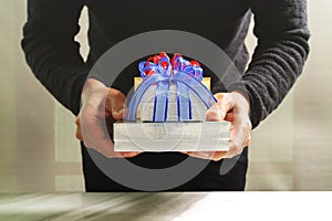 gift giving,man hand holding a gift box in a gesture of giving.blurred background,bokeh effect