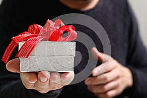 gift giving,man hand holding a gift box in a gesture of giving.blurred background,bokeh effect