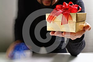 gift giving,man hand holding a gift box in a gesture of giving.blurred background,bokeh effect