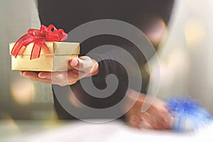 gift giving,man hand holding a gift box in a gesture of giving.blurred background,bokeh effect