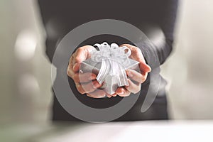 gift giving,man hand holding a gift box in a gesture of giving.blurred background,bokeh effect