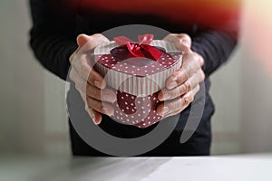 gift giving,man hand holding a gift box in a gesture of giving.blurred background,vintage effect