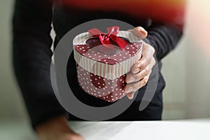 gift giving,man hand holding a gift box in a gesture of giving.blurred background,vintage effect