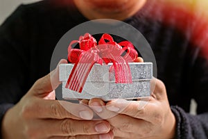 gift giving,man hand holding a gift box in a gesture of giving.blurred background,vintage effect