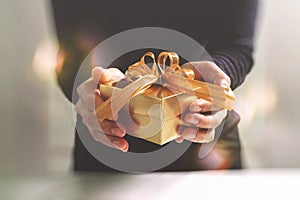 gift giving,man hand holding a gift box in a gesture of giving.blurred background,bokeh effect