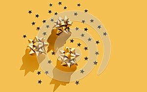 Gift golden bow with stars composition on monochrome yellow background. Winter, sale and seasonal concept. Merry Christmas, New