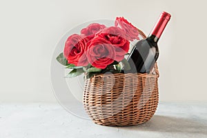 Gift hamper, bouquet of red roses, bottle of red wine on white