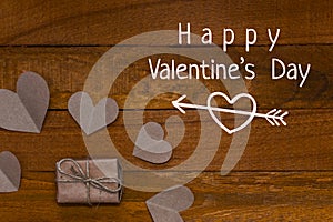 Gift and hearts of craft paper on wooden background