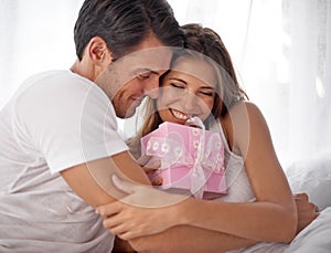 Gift, hug and couple for valentines day love celebration with care and surprise in bedroom. Man and woman in happy home