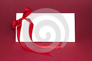 Gift isolated white card with red ribbon bow on deep red background