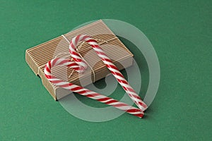 Gift Kraft Brown Color Box and Candy Canes Red and White in Heart Shape Lies on the Green Background, View From the Top. For your