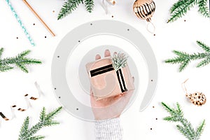 Gift in Kraft paper in a woman`s hand on a white Christmas background