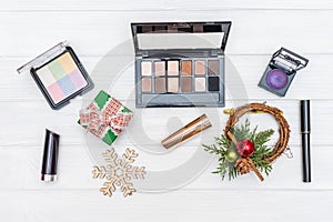 Gift make up, cosmetics and New Year ornaments and toys on white wooden background