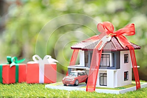 Gift new home and Real estate concept,Model house with Red ribbon and the car on natural green background