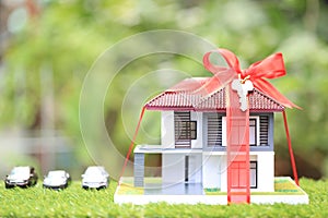 Gift new home and Real estate concept,Model house with Red ribbon on natural green background
