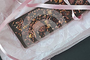 A gift pack of artisan handmade chocolate. Chocolate bars with dried fruit on dark background, front close up view.