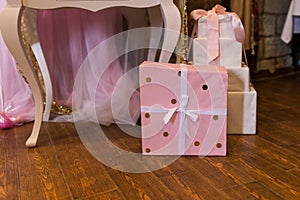 The gift is packed in pink paper with golden circles and bandaged with a white ribbon.