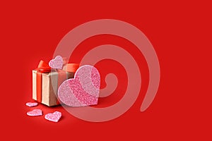 Gift and pink hearts on red background. Minimalist concept for Valentines day Mothers day, Women day or wedding.