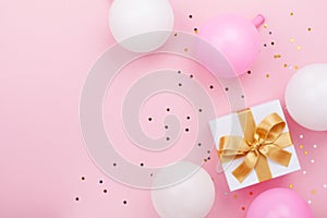 Gift or present box, balloons and confetti on pink table top view. Flat lay composition for birthday, mother day or wedding.