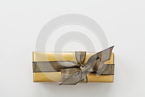 Gift or present box decorated gold ribbon on table top view. Flat lay composition for Christmas or birthday.