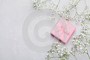 Gift or present box and flower on light table from above. Greeting card. Flat lay style.