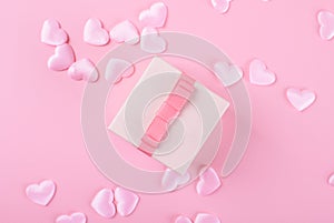 Gift or present box and heart confetti on pink table top view. Flat lay composition for birthday, mother day or wedding.