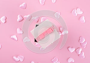 Gift or present box and heart confetti on pink table top view. Flat lay composition for birthday, mother day or wedding.