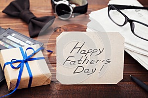 Gift or present box, newspaper, glasses, watch, bowtie and notes Happy Fathers Day on wooden table