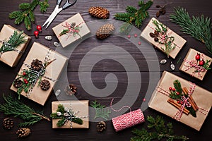 Gift or present box wrapped in kraft paper with christmas decoration on rustic wooden background from above. Flat lay style.