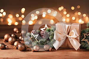 Gift or present boxes, snowy fir tree and golden holiday decoration on wooden table against magic bokeh lights. Christmas greeting