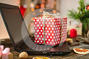 Gift red box with white polka dots on the laptop. Purchase discounts for Christmas and new year in online stores