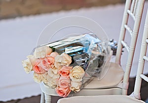 Gift rose bouquet in plastic wrapper on chair on wedding carpet
