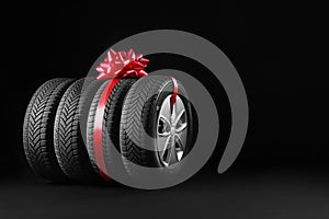 Gift set of wheels with winter tires on black background, space for text