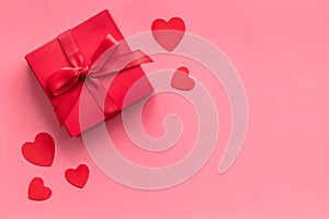 Gift to a sweetheart on Valentine`s Day. Red present box near hearts on pink background top-down copy space