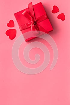 Gift to a sweetheart on Valentine`s Day. Red present box near hearts on pink background top-down copy space