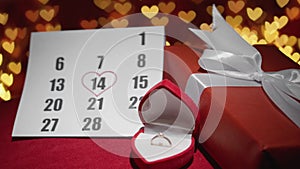 A gift for Valentines Day. Gift box on a red background with hearts. On the calendar, February 14